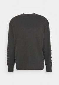 Sweatshirt noir avec un col rond, des manches longues et des poignets côtelés. Présente un texte blanc le long d'une manche et une texture lisse.