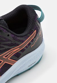 Chaussure de course noire avec tige en mesh violet, accents orange et semelle FlyteFoam bleu clair. Présente un design texturé et un talon renforcé.