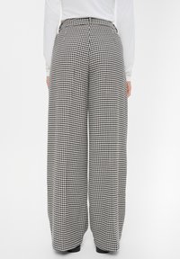 Szerokie spodnie w czarno-białą kratę houndstooth, z wysokim stanem, prostym krojem i bocznymi kieszeniami.