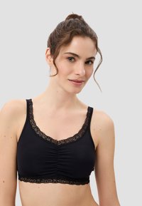 Schwarzer Bralette mit Spitzenbesatz, weichem Stoff, gerafftem Detail an der Vorderseite und verstellbaren Trägern. Glatte Textur, nahtloses Design.