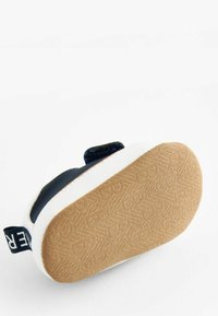 Chaussure bleu marine avec semelle blanche, présentant une semelle extérieure en caoutchouc brun texturé. Une sangle Velcro et des accents en tissu sont visibles sur le dessus.
