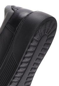 Sneaker in pelle nera con suola in gomma nera testurizzata. Caratterizzato da una punta arrotondata e una parte superiore liscia con dettagli di cucitura minimi.