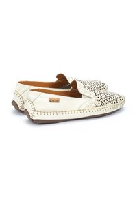 Chaussures slip-on en cuir blanc ornées de motifs floraux découpés complexes, avec des accents brun clair et une semelle en caoutchouc texturée dotée de détails de couture.