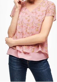 Blusa floreale rosa con maniche corte, scollatura a V, silhouette stratificata e tessuto morbido con motivi floreali gialli e rossi.