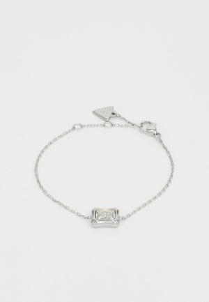 Srebrna bransoletka łańcuszkowa z prostokątnym, przezroczystym kamieniem osadzonym w wypolerowanej obręczy. Posiada regulowaną długość z zapięciem na karabińczyk.