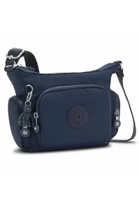 Navy nylon crossbody bag with adjustable strap, front zip pocket, circular logo patch, and keychain monkey accent. Features smooth texture.
