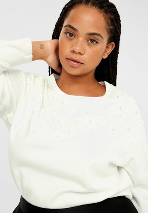 Weißer gestrickter Pullover mit rundem Halsausschnitt, verziert mit kleinen, glänzenden Perlen, die in einem dekorativen Muster über der Brust angeordnet sind.