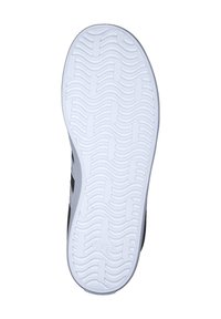 Baskets noires avec une semelle en caoutchouc blanc texturé présentant des motifs ondulés et le logo Adidas embossé près du talon.