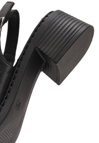 Sandale à talon haut en cuir noir avec un talon strié, un bout rond et une semelle intérieure texturée. Équipée d'une bride réglable.