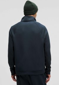 Sudadera de un navy oscuro con un collar alto, mangas raglán y puños acanalados. La textura parece suave con un diseño ajustado.