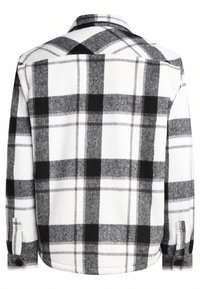 Camicia di flanella a quadri in bianco e nero con una consistenza morbida, polsini con bottoni e colletto classico. Presenta un motivo a scacchi di diverse dimensioni.