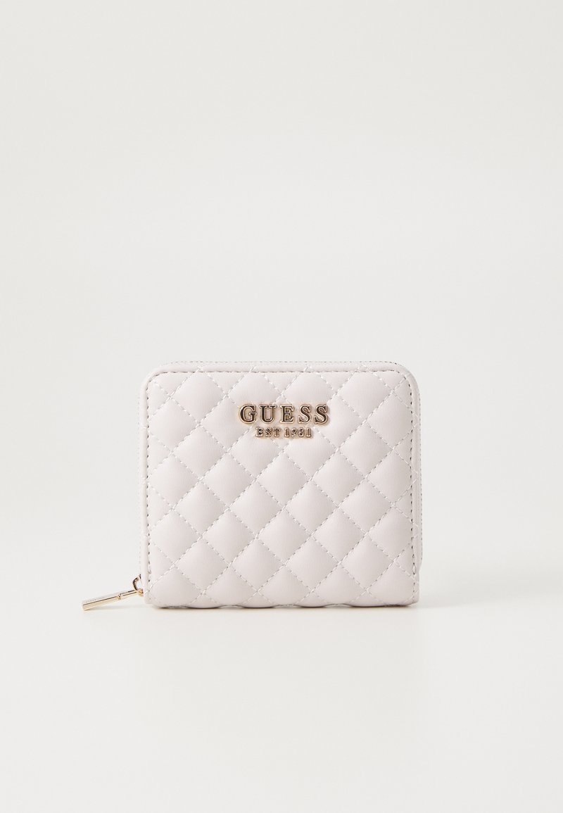 Quilted light pink wallet with gold-tone hardware, featuring the brand name "GUESS" embossed on the front and a zip closure.