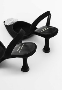 Svarta mocka högklackade skor med öppen baksida, med en skulptural klackdesign och prydda tån detaljer. Sulan har texten "Massimo Dutti Studio."