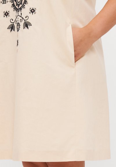 Robe beige avec poches latérales, broderies florales en noir et rose, manches courtes et coupe droite ample.