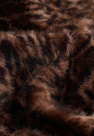 Ruda dirbtinė kailio medžiaga su tekstūruota paviršiumi, kuriame matomos tamsios juostos. Minkšta, puri medžiaga sukuria šiltą, taktilinį vaizdą.