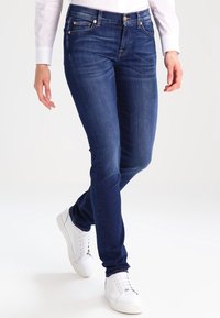 Navy blue jeans with a slim fit design, featuring subtle whiskering details, five-pocket styling, and a classic button closure.