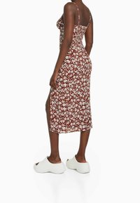 Hnědress se květinovým vzorem v bílé barvě, střední délka, slim fit, tenká ramínka, boční rozparek. V kombinaci s bílými platformovými botami. Hladká textura.