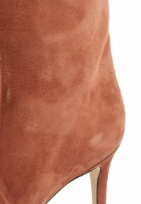 Samski stiletto potplat u boji rđe, s glatkom teksturom i elegantnim, suženim dizajnom s šiljastim vrhom i uskim potplatom.