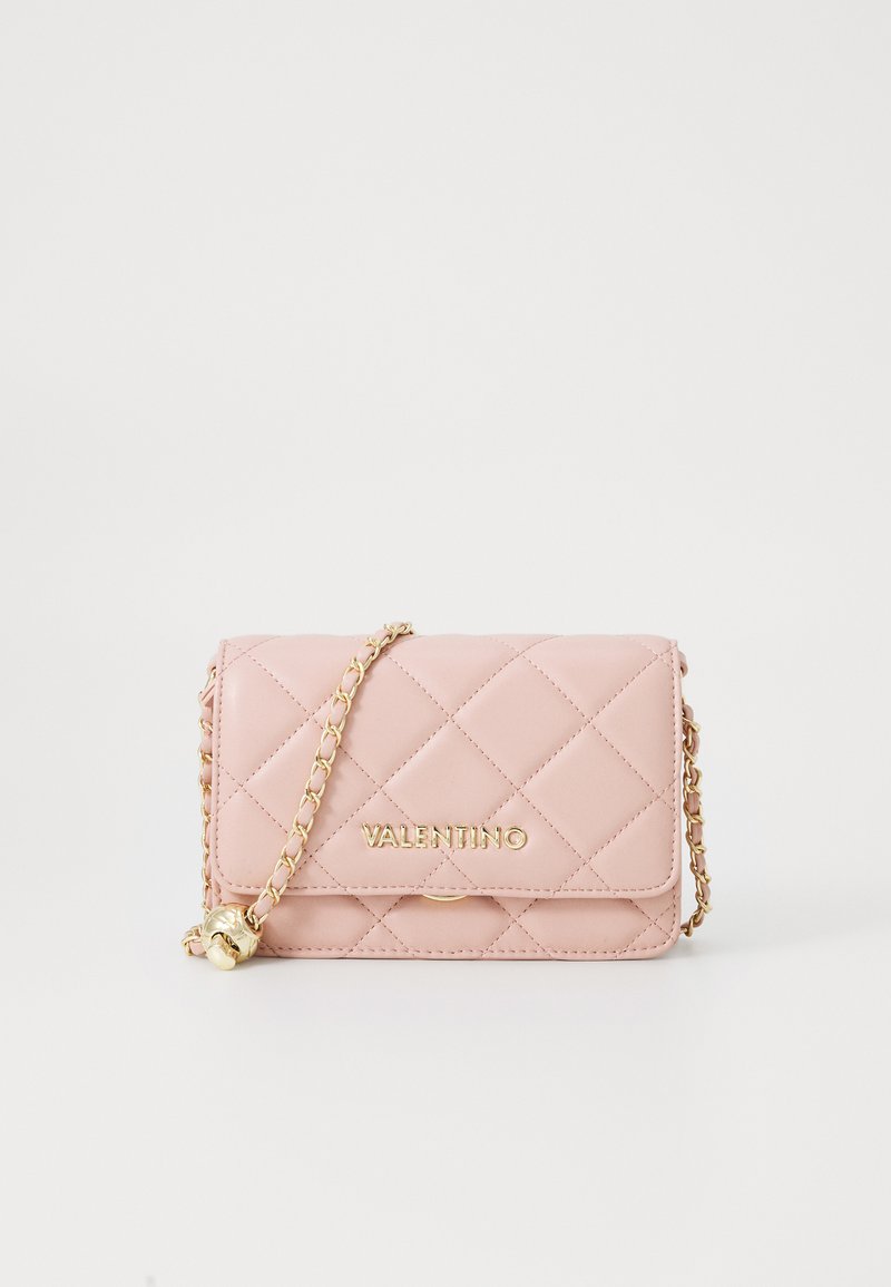 Izšūta rozā ādas rokassoma ar zelta furnitūru un ķēdes siksnu. Aprīkota ar magnētisku aizdari un logo priekšpusē. Kompakta taisnstūra forma.