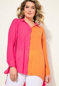 Camisa de manga larga con botones que presenta un diseño dividido en colores rosa y naranja, confeccionada en una tela suave, con cuello puntiagudo y mangas con puños.