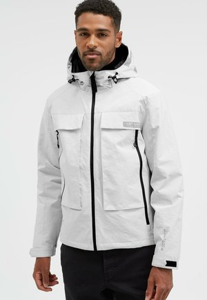 White waterproof jacket with a hood, featuring black zipper, two front pockets, and logo on the chest. Textured fabric, adjustable cuffs.