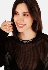 Sort mesh sweater med rund halsudskæring, der har tekstureret stof og en sølv kædedyse med sammenkædede detaljer.