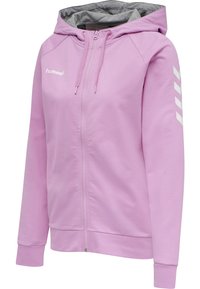 Ljusrosa zip-up hoodie med en gråfoderhuva. Utrustad med vit Hummel-logotyp och tre vita chevrons på högra ärmen. Mjuk, slät tyg.