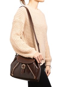 Borsa a spalla in pelle marrone con forma arrotondata, chiusura a pattina e accessori in tonalità oro. Presenta dettagli cuciti e una finitura testurizzata.