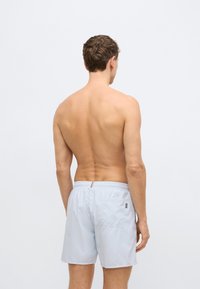 Ανοιχτό γκρι μαγιό βερμούδα με ελαστική μέση, μια πίσω τσέπη και μια μικρή ετικέτα με λογότυπο. Ομαλή υφή και μήκος μέχρι το μέσο του μηρού.