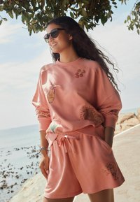 Set di felpa e pantaloni corti in cotone rosa con disegni ricamati, raffiguranti una brocca, fiori e un motivo di bevanda, vestibilità rilassata e vita elasticizzata.