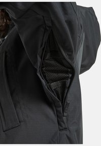 Schwarze wasserdichte Jacke mit Reißverschlusstasche; verfügt über ein Netzfutter und verstärkte Nähte für bessere Haltbarkeit. Glattes Gewebe mit mattem Finish.