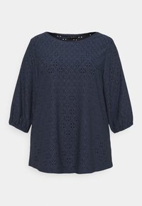 Navy blue shirt with a round neck, three-quarter puff sleeves, and eyelet pattern creating diamond shapes across the fabric.