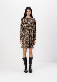 Φορεμάκι με λεκέ ζωής λεοπάρ, μακριά μανίκια, εφαρμοστό μπούστο και φουφού skirt. Φορεμένο με μαύρες δερμάτινες μπότες έως το γόνατο με μυτερές μύτες.