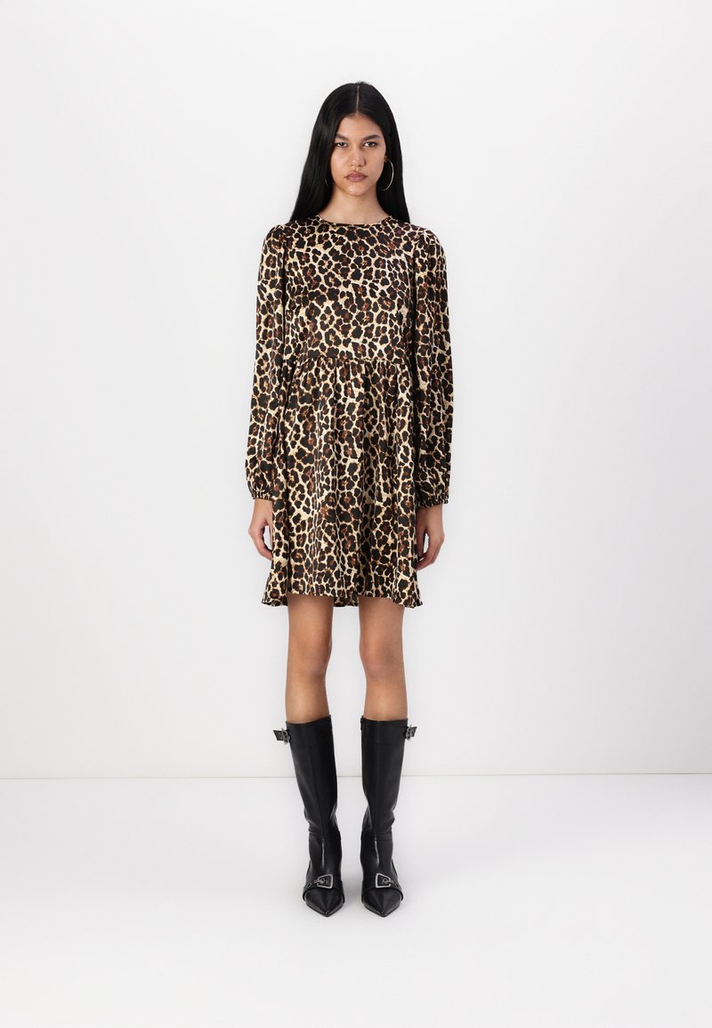 Φορεμάκι με λεκέ ζωής λεοπάρ, μακριά μανίκια, εφαρμοστό μπούστο και φουφού skirt. Φορεμένο με μαύρες δερμάτινες μπότες έως το γόνατο με μυτερές μύτες.