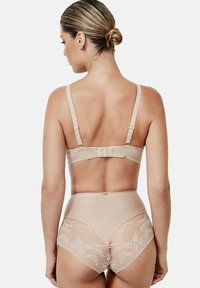 Ensemble de lingerie beige comprenant un soutien-gorge avec dentelle et bretelles réglables, ainsi que des culottes taille haute avec des accents en dentelle florale.