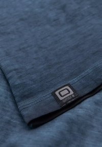 Maglietta blu con una texture morbida, dotata di un'etichetta con la scritta "amore". Il design ha una finitura minimalista e liscia, senza motivi.