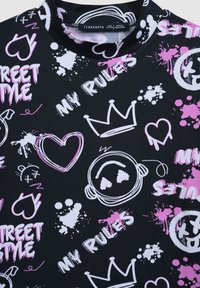 Czarna tkanina z kolorowymi grafikami w stylu graffiti, w tym serca, korony i tekst w białym i różowym kolorze. Gładka tekstura.