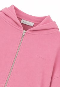Sweat à capuche rose avec fermeture éclair argentée et étiquette "OH APRIL" à l'intérieur du col et brodée sur la poitrine.