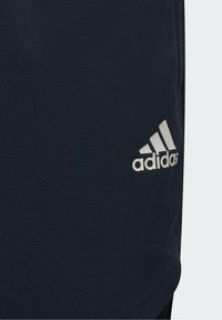 Navy athletic shorts made of textured fabric, featuring a prominent white Adidas logo on the left leg. Smooth, adjustable waistband.