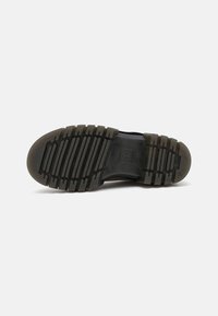 Suela de zapato de goma con un patrón de agarre texturizado, que presenta crestas y surcos alternos en negro y gris, diseñada para ofrecer tracción y durabilidad.