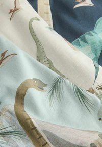 Wzory różnych kolorowych dinozaurów i palmowych liści na miękkim materiale o złożonej fakturze.