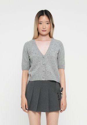 Grijze korte mouw cardigan met een V-hals, voorzien van parelaccenten en knopen aan de voorkant, gecombineerd met een donkergrijze geplooide rok.