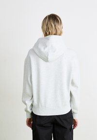 Grå hettegenser med avslappet passform, ribbestrikkede ermer og hem. Myk tekstur, ensartet design, synlig søm og stor hette.