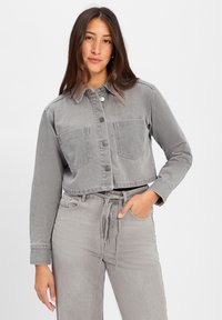 Przycięta szara kurtka dżinsowa z dwiema przednimi kieszeniami i guzikami, w połączeniu z pasującymi szarymi spodniami z wiązaniem w talii oraz detalem kieszeni.