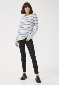 Gestreifter Pullover mit horizontalen Linien in Beige, Hellblau und Braun, mit langen Ärmeln und einer lockeren Passform, kombiniert mit schwarzen Hosen und Schuhen.