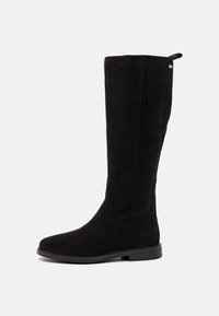 Botte noire en daim montant jusqu'au genou, avec petit talon, bout arrondi, et languette à l'arrière, vue de côté sur fond blanc.