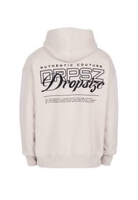 Jasno beżowa bluza z kapturem, wykonana z miękkiego materiału. Na plecach widnieje duży czarny napis "AUTENTYCZNY KREATYWNIK DRPSZ Dropsize".