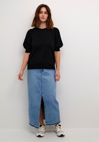 Black short-sleeve top with puffed sleeves, paired with a light blue denim maxi skirt featuring a front slit, and white sneakers.