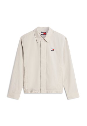 Μπεζ ελαφρύ μπουφάν με γιακά, κρυφά κουμπιά στο μπροστινό μέρος, ελαστική μέση, πλευρικές τσέπες και μικρό λογότυπο Tommy Jeans στο στήθος και μέσα στον γιακά.
