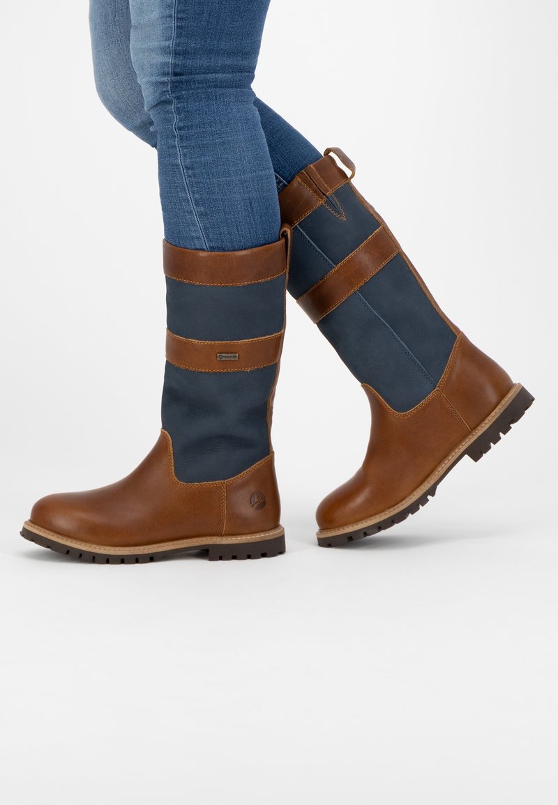 Bruna läder- och marinblå textil knähöga stövlar med platt sula, rund tå och dekorativa bruna remmar. Har en draglo plock i bak.